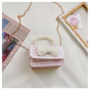 Detail of pink tweed girl's bag with large pearl bow, lace trim and pearl handle