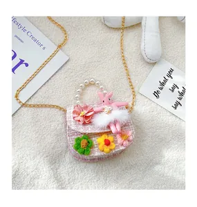 Detail of pink tweed girl's bag with knit flowers, pearl handle, and plush bunny charm