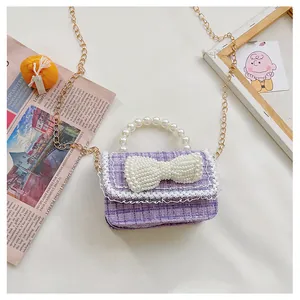 Detail of pink tweed girl's mini bag with pearl bow, lace trim, and gold chain strap