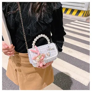 Détail du sac tweed pour enfant avec poignée perle, chaîne dorée et breloque lapin