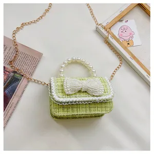 Detail of green tweed mini bag with pearl handle, bow decoration and white lace edges