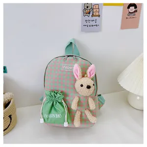 Detail of cute pink and green plaid kids backpack with a plush bunny and side pouch