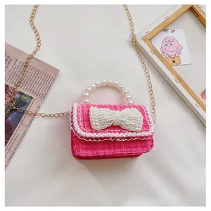 Close-up of pink tweed child handbag featuring a large pearl bow and lace trim details