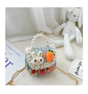 Detailed shot of tweed girls purse with pearl handle, plush bunny, and gold chain strap
