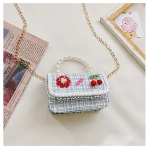 Detail of tweed girls crossbody bag with pearl handle, lace trim, and cherry charms