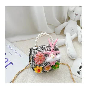 Close-up of kids tweed crossbody bag with pink rabbit doll, pearls and gold chain