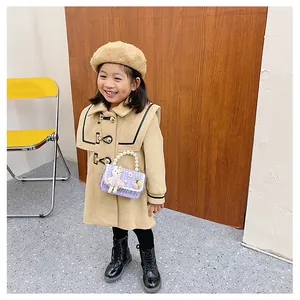 Fillette en manteau de laine avec sac en tweed violet, poignée en perles et lapin peluche