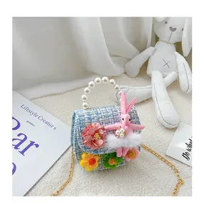 Detail of tweed kids crossbody bag with pearl handle and plush bunny ornament