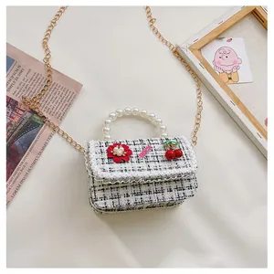 Detail of tweed girl's handbag with pearl handle, metal chain and floral charms
