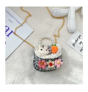 Detail of tweed kids crossbody bag with pearl handle and plush bunny decoration