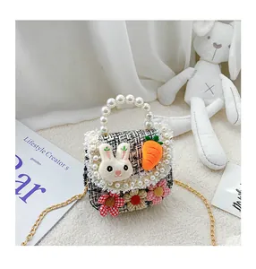 Detail of tweed girls crossbody bag with pearl handle and plush bunny decoration
