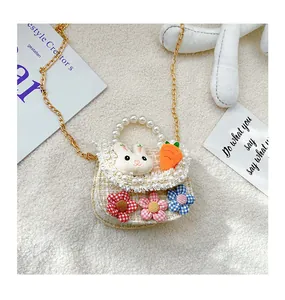 Detail of tweed girls' crossbody bag with pearl handle and plush rabbit decoration