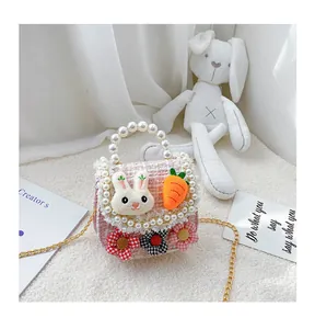 Close-up of pink tweed kids crossbody bag with pearl handle and plush rabbit decor