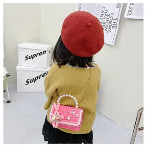 Détail du sac enfant en tweed rose avec poignée en perles et breloque lapin mignon
