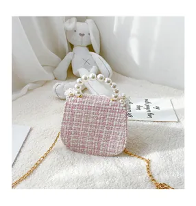 Detailed shot of pink tweed girls' mini purse with pearl handle and golden chain strap
