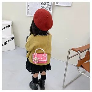 Sac enfant en tweed rose avec poignée en perles et breloque lapin porté par mannequin