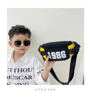 Close-up detail of a boy's black nylon chest bag with 1986 print and yellow accents
