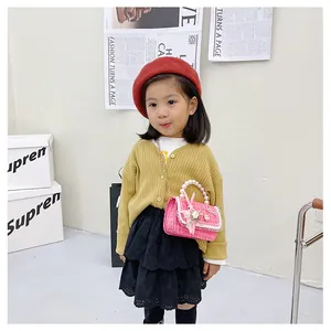 Détail d'un sac à main enfant en tweed rose avec anse perlée, lapin peluche et fleurs