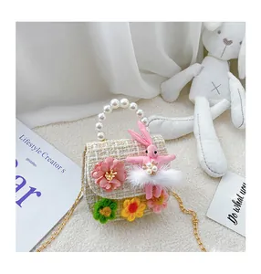 Close-up of girls tweed handbag with pearl handle, plush bunny and gold chain strap