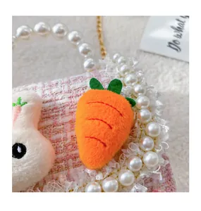 Detail of pink tweed girl's bag with pearl handle and plush bunny carrot decor
