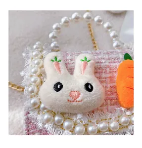 Detail of pink tweed girl's bag with plush bunny, carrot charm and pearl handle