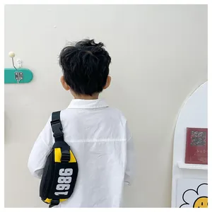 Kid's yellow and black crossbody chest bag with 1986 print shown on a child's back