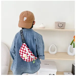 Detail of kids checkerboard chest bag with adjustable letter strap on a denim jacket