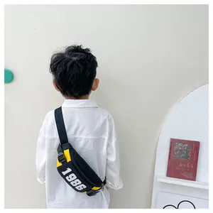Detailed view of child wearing black and yellow crossbody bag with 1986 number print