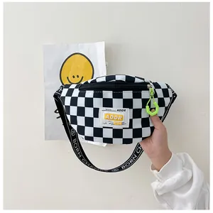 Detail of kids checkerboard chest bag featuring neon green zipper and ADDR logo patch