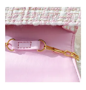Detailed macro view of pink tweed fabric and gold metal chain buckle on the cute kid purse