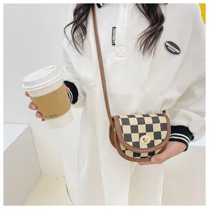 Detail of girl's saddle bag featuring brown checkerboard pattern and gold swivel lock