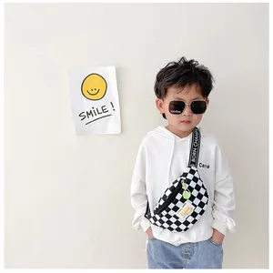Close-up of checkerboard canvas kids chest bag with green zipper pull and logo detail