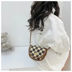Detail view of a retro checkered saddle bag with brown leather strap and gold metal lock