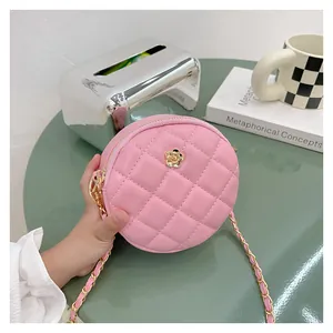 Close-up of pink quilted round mini bag featuring golden flower buckle and chain strap