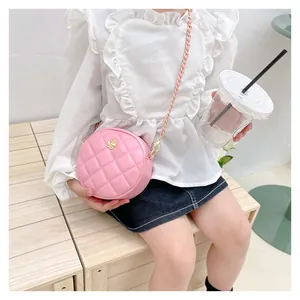 Detail of pink quilted round kids crossbody bag with golden flower and chain strap
