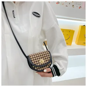 Detail of girls' houndstooth saddle bag with gold metal buckle and black leather strap