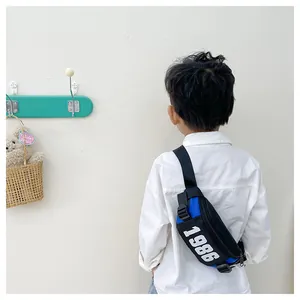 Close-up of children's blue and black crossbody bag with white 1986 print and buckle