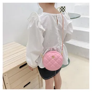 Rear view of child wearing a pink quilted round crossbody bag with gold chain strap