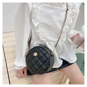 Close-up of children's quilted round bag with gold flower clasp and woven chain strap