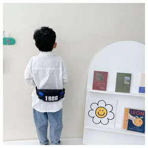Rear view of a child wearing a blue and black crossbody chest bag with 1986 print