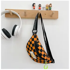 Detail view of checkered kids chest bag with orange neon hook and logo strap