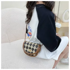 Detail of a plaid saddle crossbody bag with brown leather trim and a golden twist lock