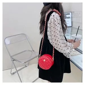 Detail of red quilted round kids handbag with golden floral clasp and chain strap