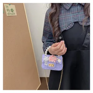 Detail of lavender girls crossbody bag with pearl handle and decorative floral charms
