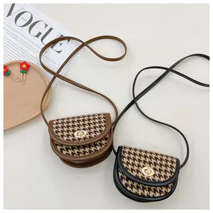 Detail of houndstooth plaid mini saddle bags with gold metal clasps in black and brown