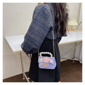 Detail of purple tweed girls bag featuring pearl handle and pink flower charm