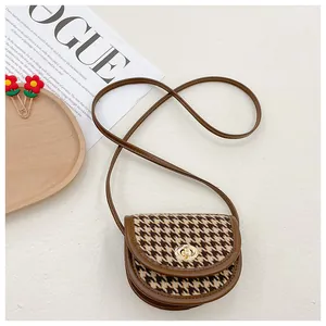 Macro view of vintage brown saddle bag with coffee houndstooth pattern and golden clasp