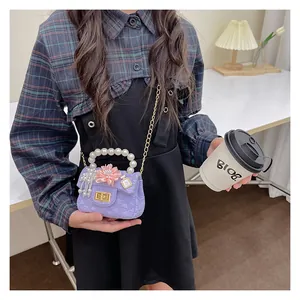 Detail of purple mini bag featuring pearl handle, floral decor and gold chain strap