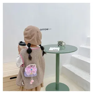 Detail der lila Kinderhandtasche mit rosa Spitzenschleife, Perlengriff und Goldkette