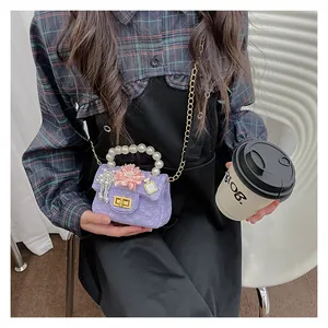Detail of a purple quilted girls' mini bag with pearl handle and flower pendant charms